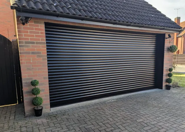 Wide black roller garage door on a modern double garage